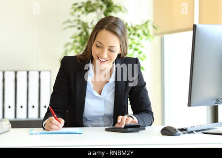 Office worker calculating budget using calculator and writing on a document Stock Photo