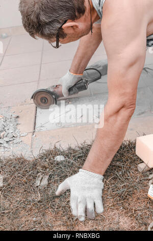 A circular saw. A man sawing ceramic tiles. Worker sawing a tile on a circular saw. Selective focus Stock Photo