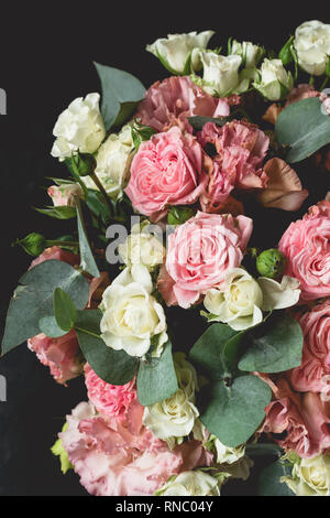 Bouquet of roses and eucalyptus over black background. Wedding, birthday flowers bouquet Stock Photo