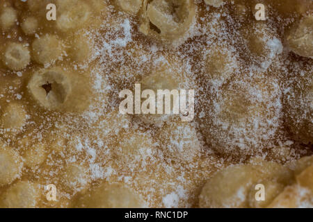 Macrophoto. European dessert angel wings. Interesting tech tour deep fried dough strips with powdered sugar. Site about the kitchen, pastries, sweets. Stock Photo