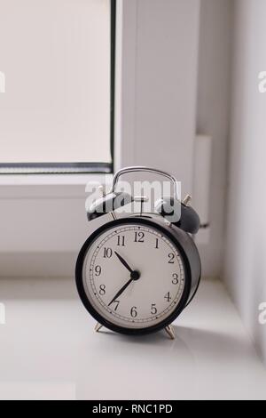 old mechanical alarm clock black and white clock is on the windowsill Stock Photo