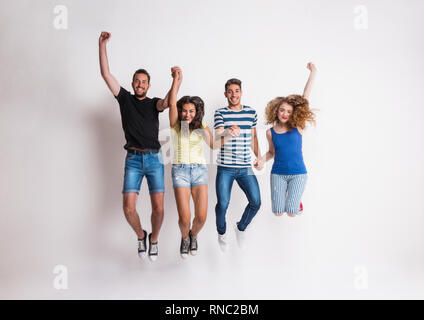 Portrait of joyful young group of friends jumping in a studio. Stock Photo