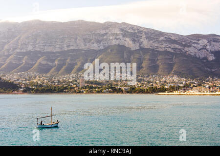 A small fishing boat entering the port in Denia, Spain. Montgó mountain is in the background Stock Photo