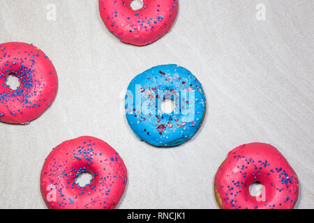 Blue and pink glazed donuts with sprinkles on light background, top view. Stock Photo