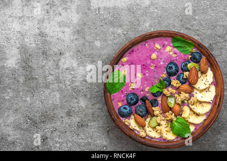Healthy breakfast. acai smoothie bowl with banana, blueberry, granola, almonds, pumpkin and chia seeds. detox food concept. top view with copy space Stock Photo