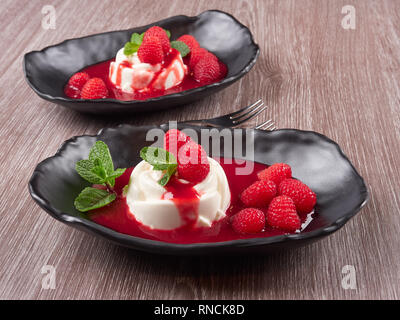 Vanilla bean pannacotta with raspberry coulis, fresh raspberries, and mint leaves Stock Photo