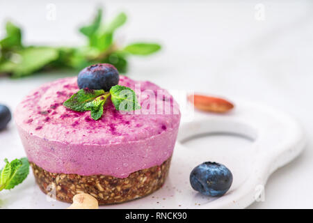 blueberry and acai vegan cashew cake with fresh berries, mint, nuts. healthy vegan food concept. close up Stock Photo