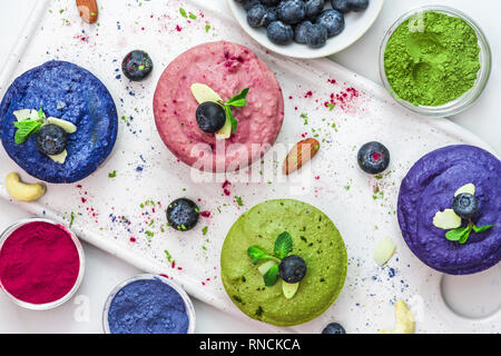 healthy vegan desserts. assortment of raw cashew cakes with matcha, acai, blueberry, mint and nuts. gluten free diet. top view. flat lay Stock Photo