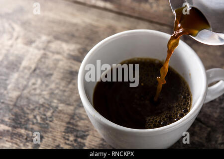 Pouring hot coffee in a cup on wooden table. Stock Photo