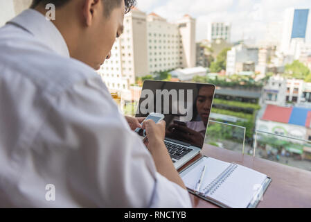 Young Asian businessman using smartphone on the balcony