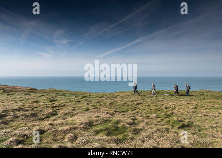A group of walkers and a dog walking along the South West Coast Path on the North Cornwall coast. Stock Photo