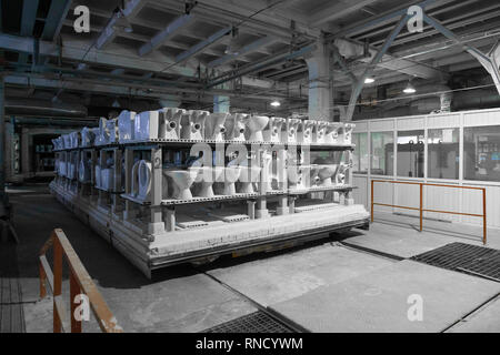 ceramic toilets and sinks on the shelves in the production shop Stock Photo