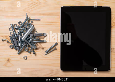 slide of bolts and nuts and a tablet with an empty screen lie on the table Stock Photo