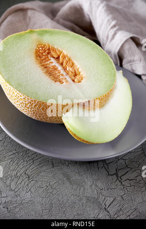 Cantaloupe melon sliced on grey plate, copy-space Stock Photo