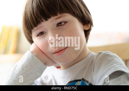 Boy is sitting and resting his head on his arm Stock Photo