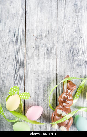 Easter greeting card background with bunny rabbits and colorful eggs, holiday ribbon and tulip flowers, wooden background top view copy space Stock Photo