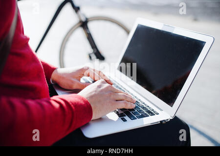 A midsection of businessman sitting on bench in city, using laptop. Copy space. Stock Photo