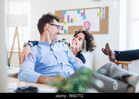 Two young cheerful businesspeople relaxing in a modern office. Stock Photo