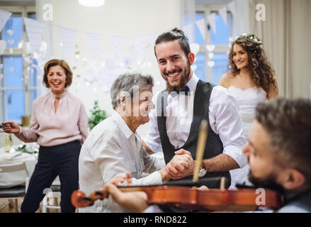 A young groom dancing with grandmother on a wedding reception. Stock Photo