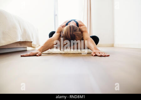 Young woman doing yoga exercise indoors in a bedroom. Copy space. Stock Photo