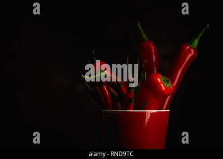 Fresh red and spicy chilli peppers on dark background. Stock Photo