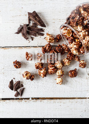 Chocolate popcorn and pieces of chocolate on a wooden table