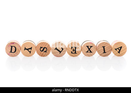 Word Dyslexia from circular wooden tiles with letters children toy. Concept of learning difficulty disorder spelled in children toy letters. Stock Photo
