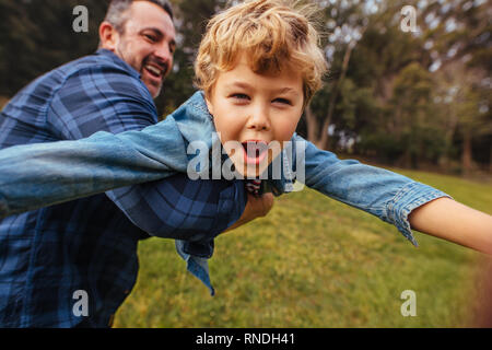 Son with his father having fun in park. Happy boy playing with dad outdoors. Little boy lifted by his father.