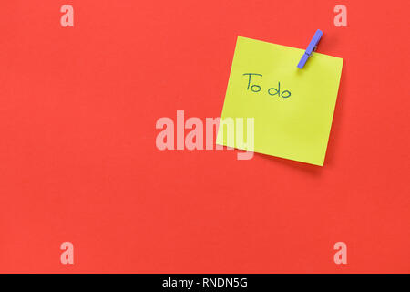 Yellow sticky note with text 'To do'  isolated on a red background and copy space Stock Photo