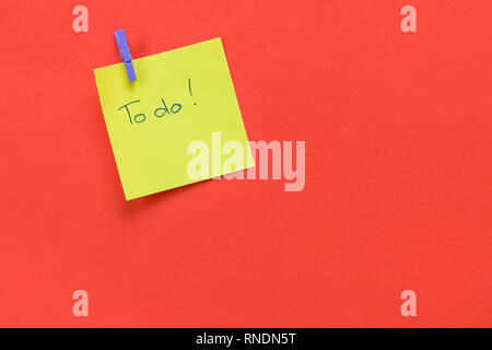 Yellow sticky note with text 'To do'  isolated on a red background and copy space Stock Photo