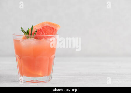Refreshment grapefruit cocktail with rosemary and ice on white background. Healthy citrus summer drink. close up Stock Photo