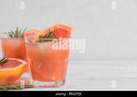 fresh grapefruit summer alcohol cocktails in glasses, ice and rosemary on white background. close up Stock Photo