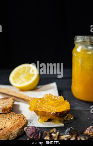 Spoonful of honey on dark rustic background. Crystallized home-made honey in jar, low-key shot with copy space Stock Photo
