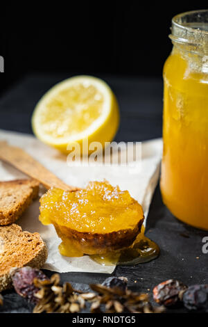 Spoonful of honey on dark rustic background. Crystallized home-made honey in jar, low-key shot Stock Photo