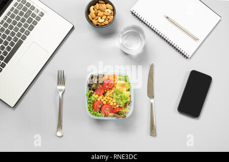 Healthy business lunch in office, salad for snack, almonds, water on blue table. Top view with copy space. Concept healthy nutrition. Lunchbox. To do  Stock Photo