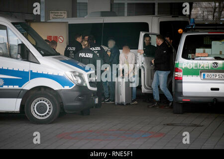 Frankfurt, Germany. 18th Feb, 2019.  Handcuffed at the airport, one man pushes his suitcase between police officers, while another carries his belongings in cardboard boxes on his arm. Both men are to be deported to Afghanistan this evening with a chartered plane. Photo: Boris Roessler/dpa - ATTENTION: The persons were pixelated for reasons of personality rights Credit: dpa picture alliance/Alamy Live News Stock Photo