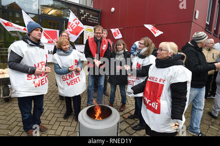 Bremen, Germany. 19th Feb, 2019. Participants of a warning strike stand at the entrance to the 'Allgemeine Berufsbildende Schule' at Steffensweg and warm themselves by a fire. The Education and Science Union (GEW) has called for a full-day warning strike at schools in Bremen and Bremerhaven. Credit: Carmen Jaspersen/dpa/Alamy Live News Stock Photo