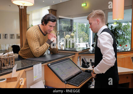 Dierhagen, Germany. 29th Jan, 2019. Christian Schenk, GDR Decathlon Olympic Champion 1988 in Seoul and current Sports and Event Manager at the Hotel 'Fischland', stands at the reception of the hotel and is informed by receptionist Sebastian Plackmeier. Credit: Bernd Wüstneck/dpa-Zentralbild/dpa/Alamy Live News Stock Photo