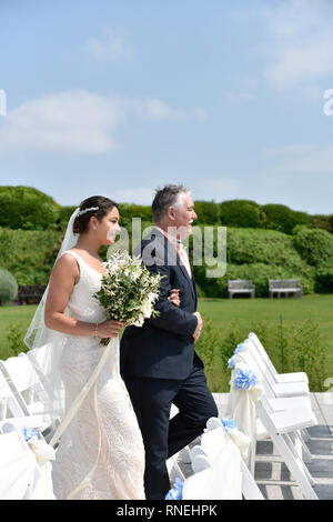 Beautiful white couple get married by the sea on a glorious Summer day in a traditonal white wedding Stock Photo