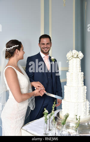 Beautiful white couple get married by the sea on a glorious Summer day in a traditonal white wedding Stock Photo
