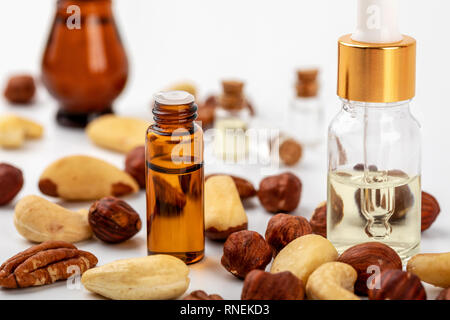 nut oil perfume bottles and nuts on white background Stock Photo