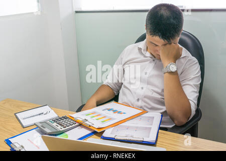 Young businessman feels headache and stressed with financial reports Stock Photo