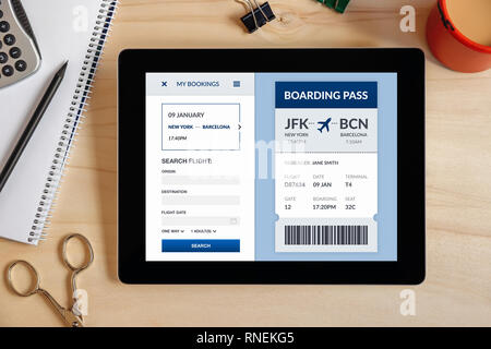 Boarding pass concept on tablet screen with office objects on wooden desk. All screen content is designed by me. Top view Stock Photo