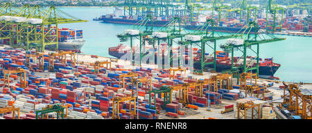 Aerial panorama of cargo ships in Singapore industrial port harbor by pier with freight cranes and goods containers, seacsape at background Stock Photo