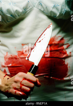 A woman covered in blood holding a knife. Stock Photo