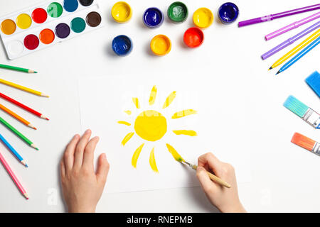 Kid hands painting at the table with art supplies, top view Stock Photo