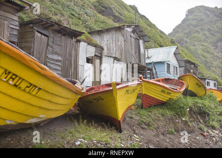 Old boats and a huts on a remote beach. Stock Photo