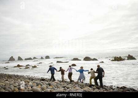 Group of people walking along a beach holding hands Stock Photo