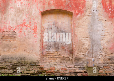 Old weathered painted wall background texture. Red dirty peeled plaster wall with falling off flakes of paint. Stock Photo