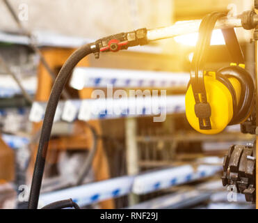 Safety noise at the workplace, yellow headphones against noise hang in the workshop for the manufacture of PVC windows Stock Photo